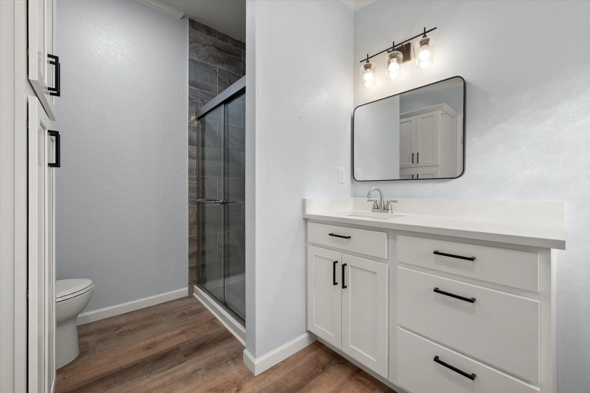 White vanity with matte black hardware, integrated sink, and rectangular mirror