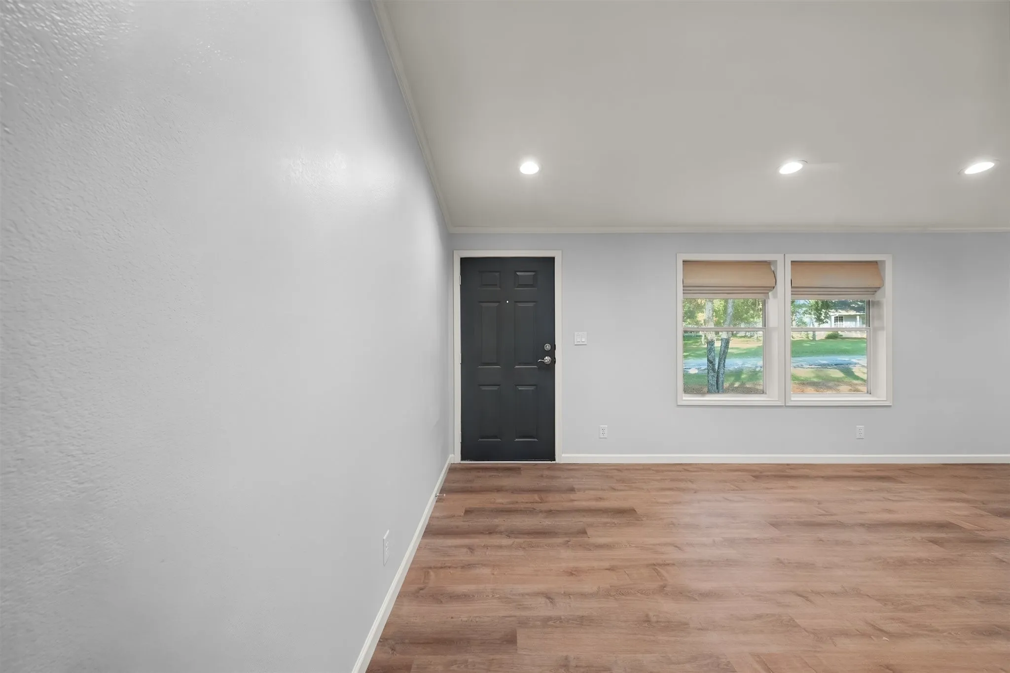 Vaulted ceiling with recessed lighting, wood-finish flooring, and white trim