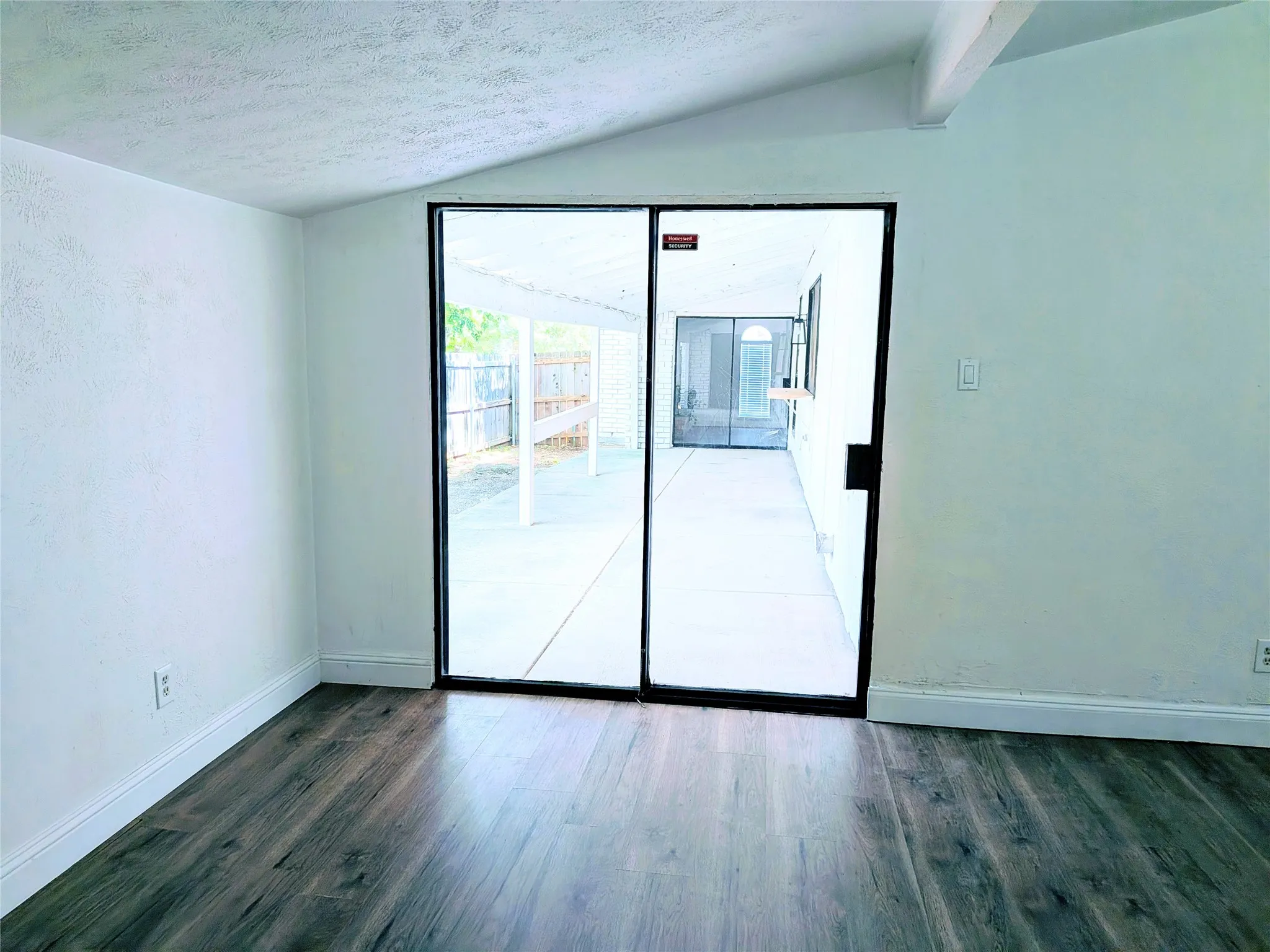 Wood-finish flooring, white walls, and vaulted ceiling with exposed beam