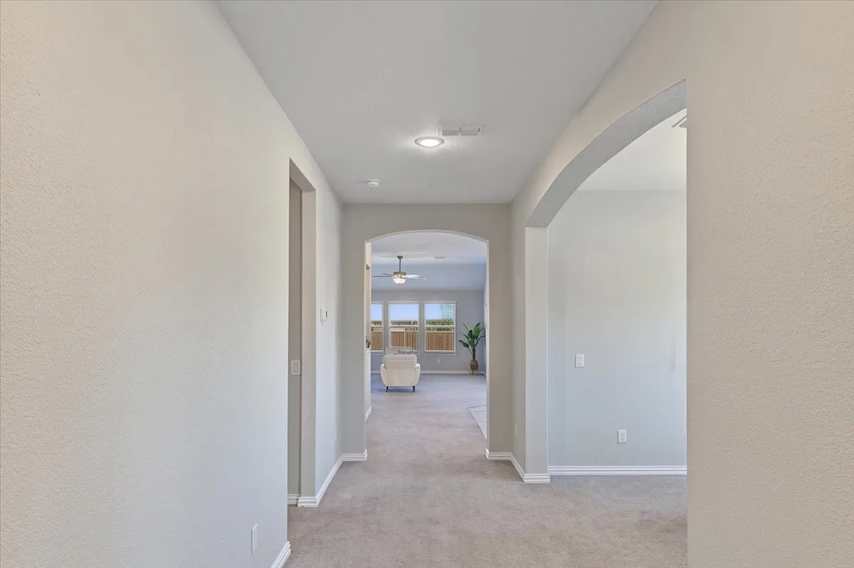 Arched doorways, recessed lighting, and light-toned walls with carpeted flooring