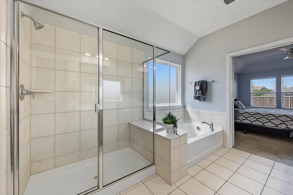 Step-in glass-enclosed shower with tile surround, built-in soaking tub, and tiled flooring