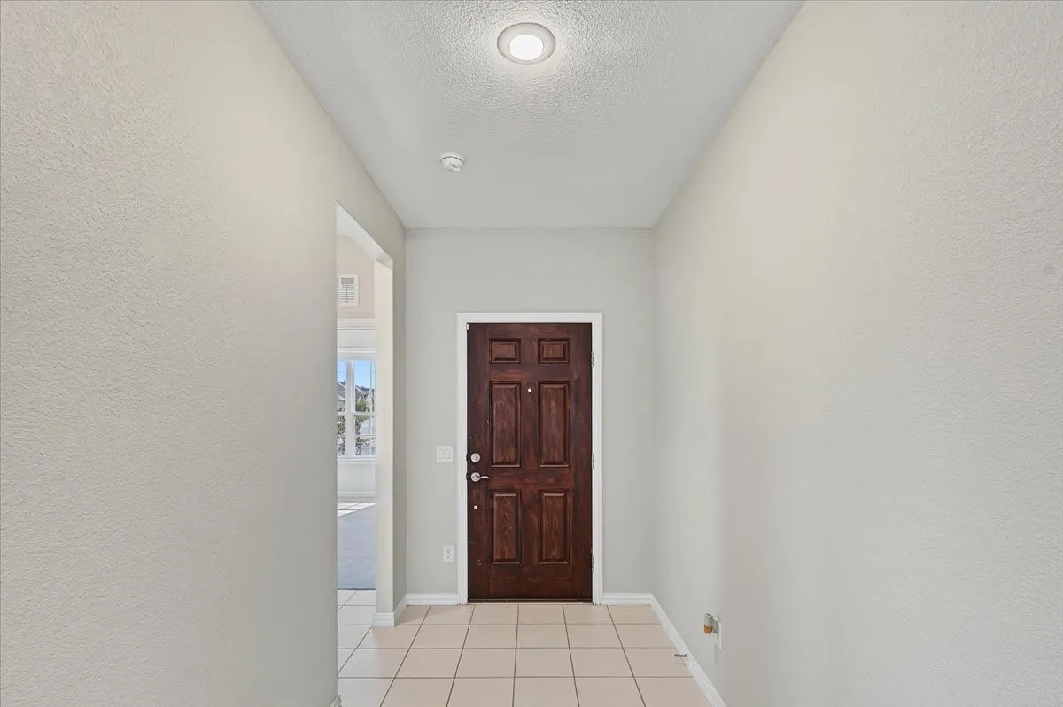 Entryway featuring a paneled wood door, recessed ceiling light, and square tile flooring