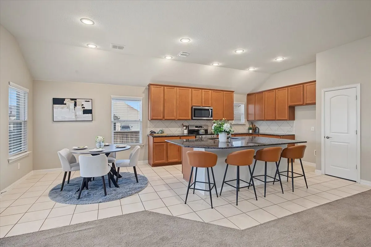 Kitchen featuring a center island, wood cabinetry, stainless steel appliances, and tile flooring