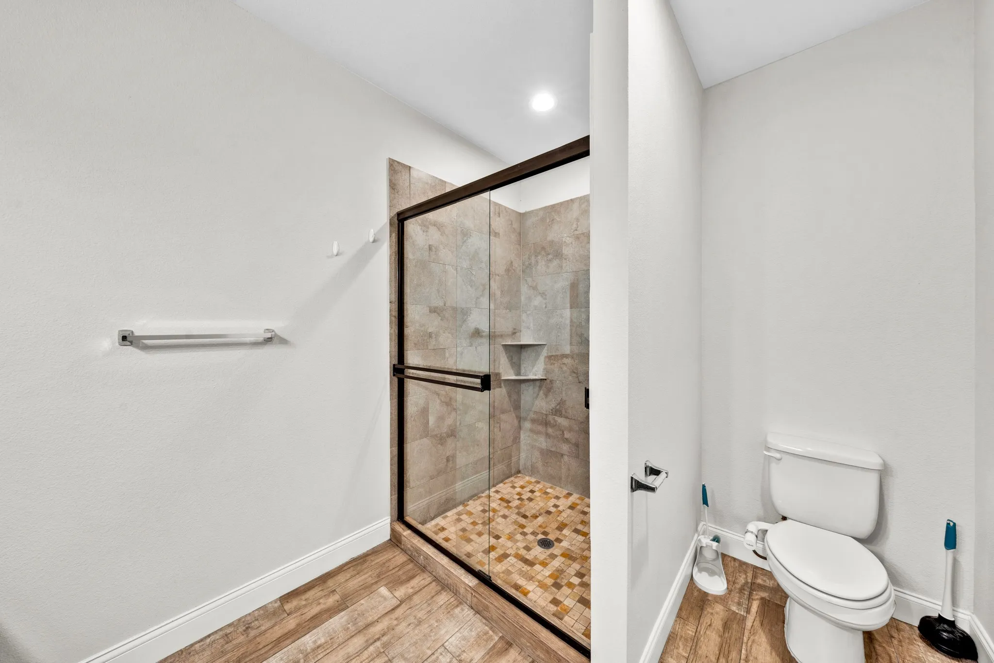 Walk-in shower with glass enclosure and floor-to-ceiling tile, featuring a built-in shelf