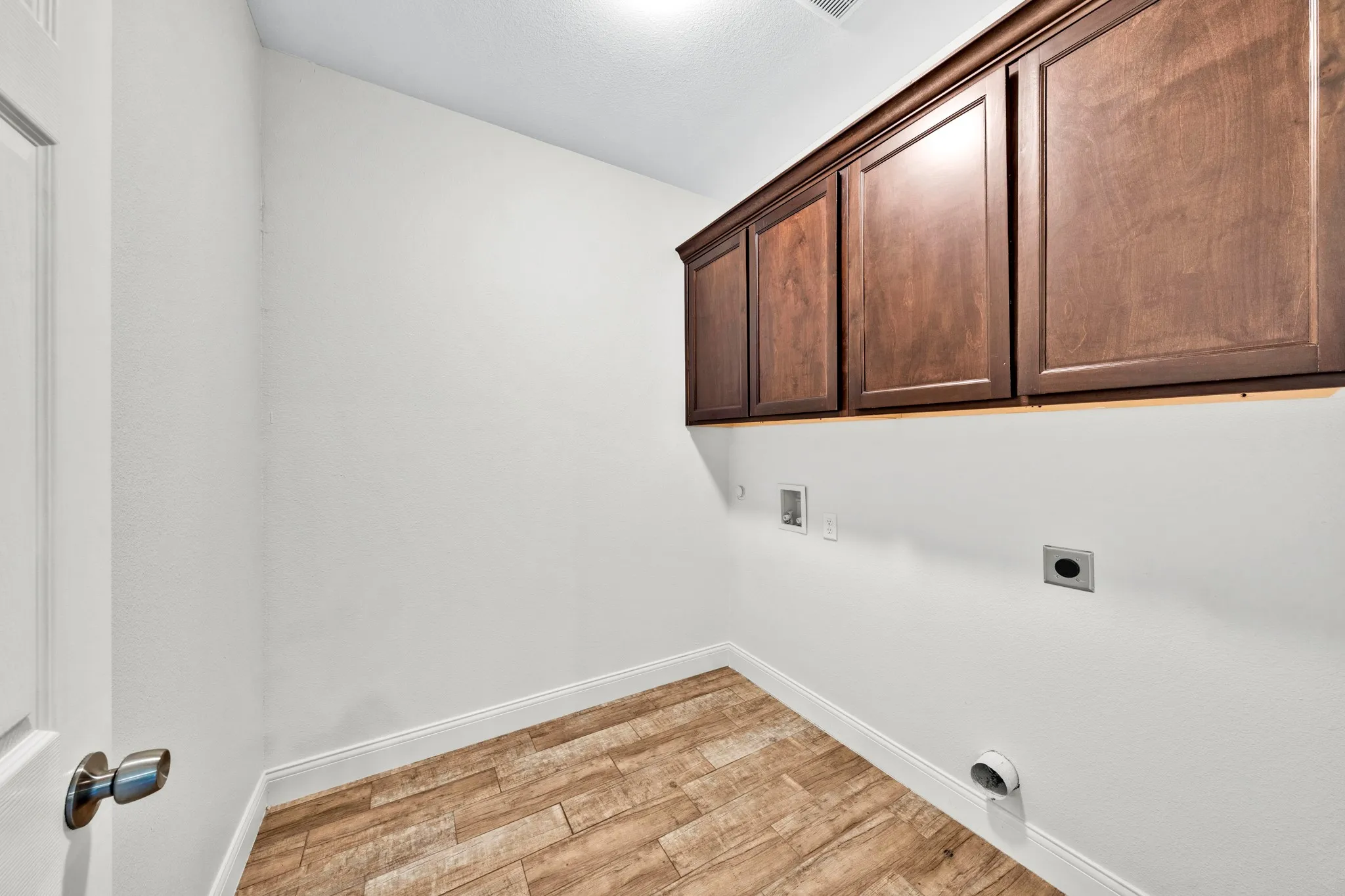 Wood-finish flooring, white walls, and dark wood cabinetry provide functional space