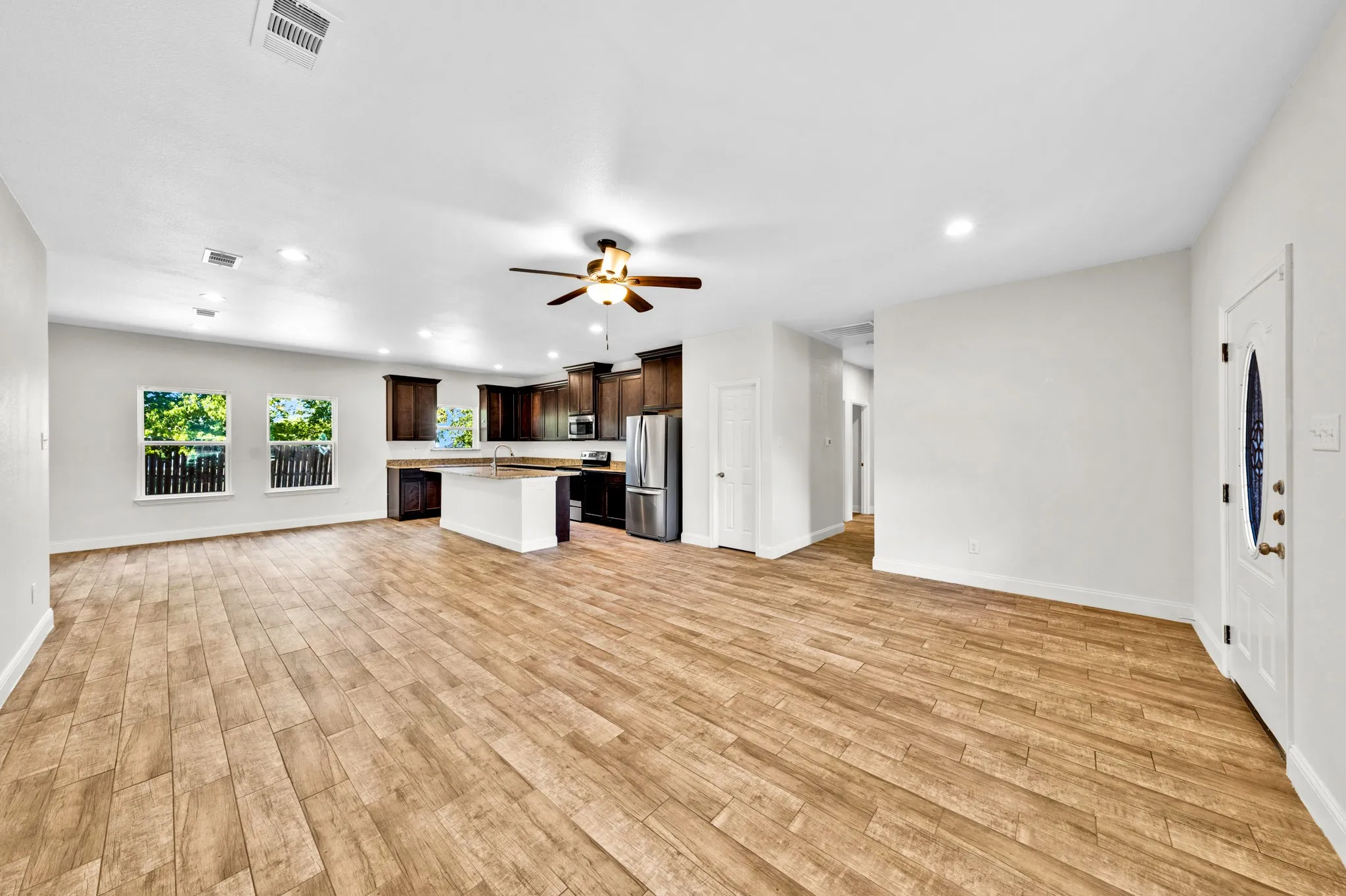 Open-concept living space with wood-finish flooring, recessed lighting, and a ceiling fan