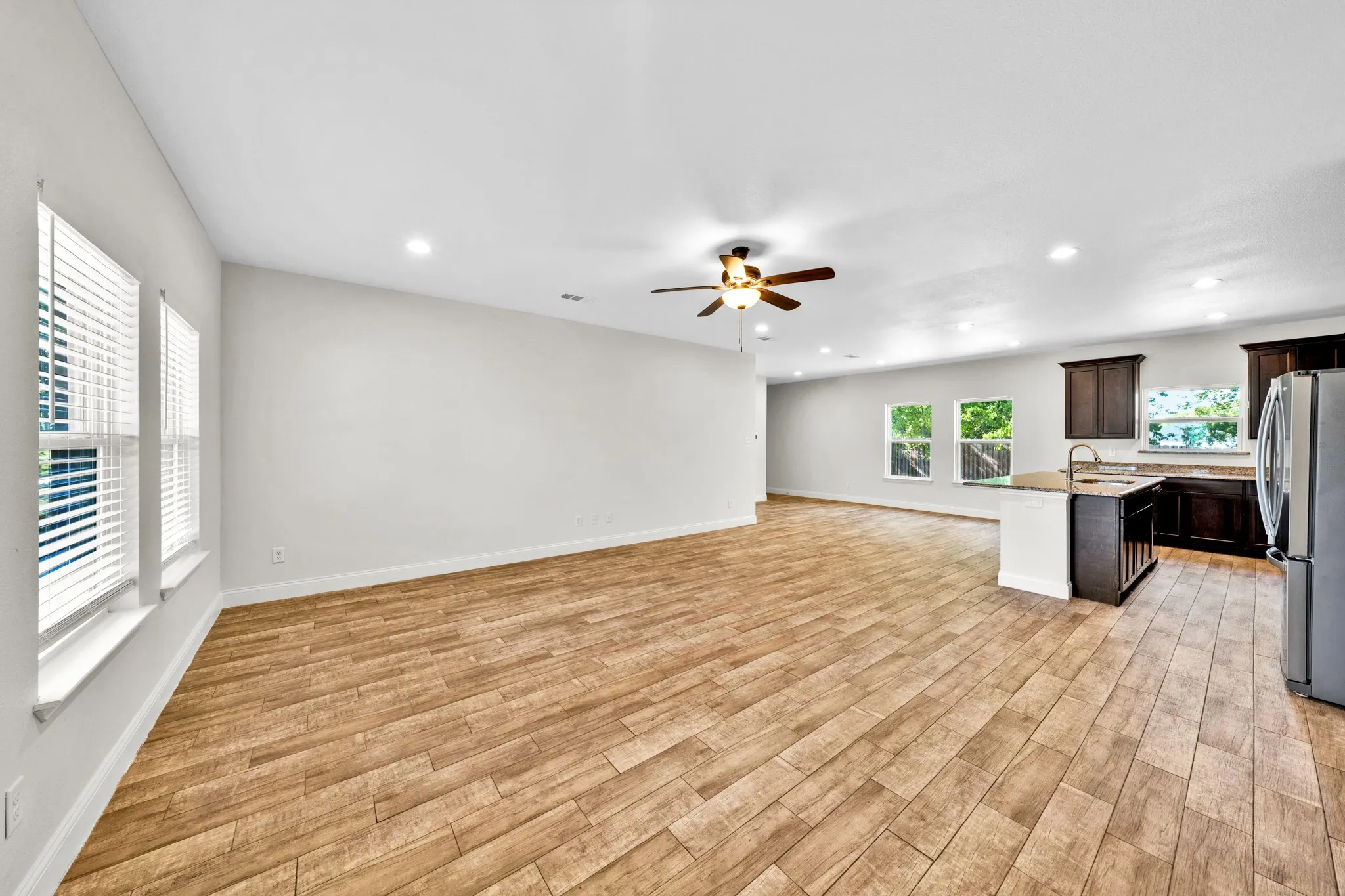 Expansive living area featuring wood-finish flooring, recessed lighting, and a ceiling fan