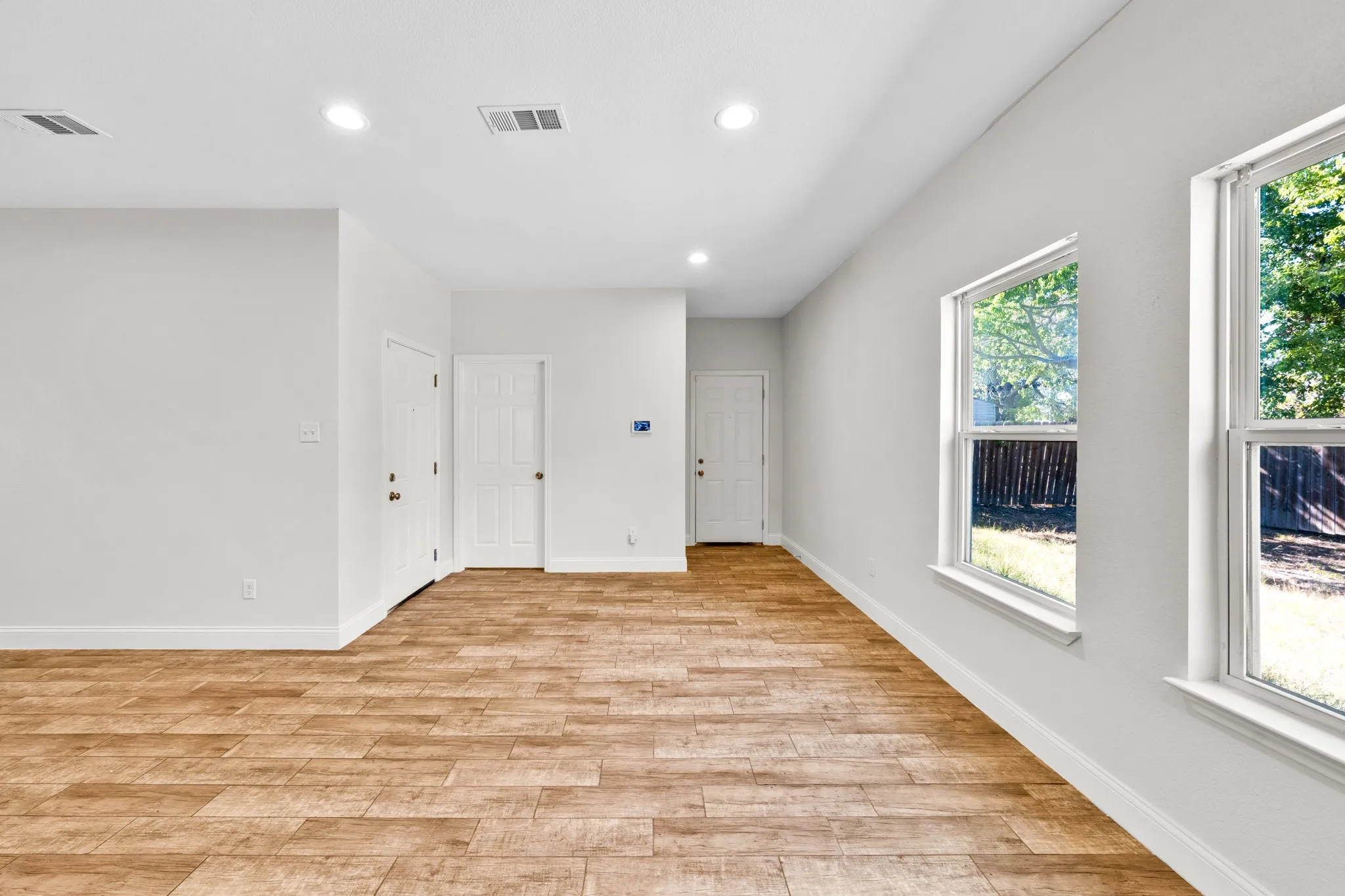 Recessed lighting, wood-finish flooring, white paneled doors, and multiple windows