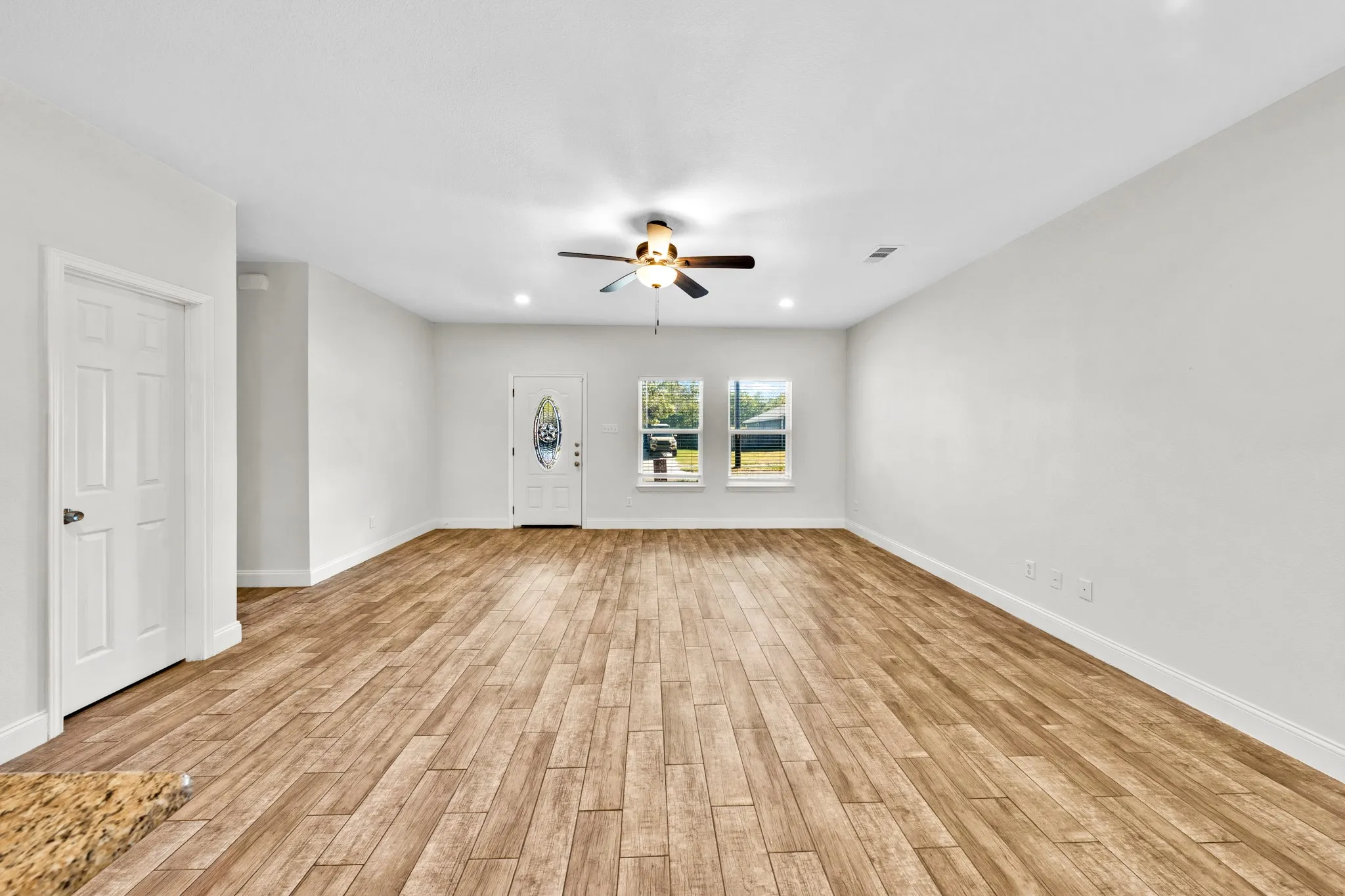 Spacious room featuring wood-finish flooring, recessed lighting, and a ceiling fan