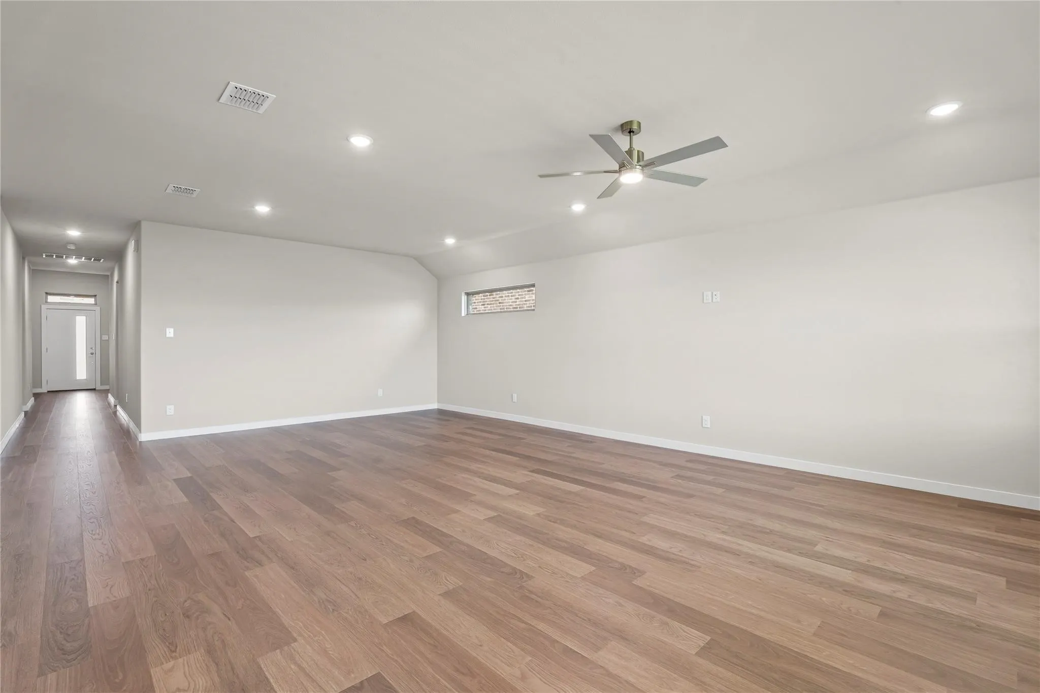 Expansive open-concept room featuring wood-finish flooring, recessed lighting, a modern ceiling fan, and a transom window