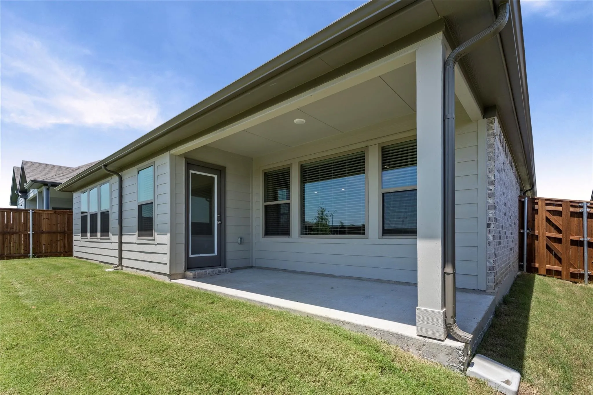 Covered patio with a concrete surface, exterior siding, and brick accents