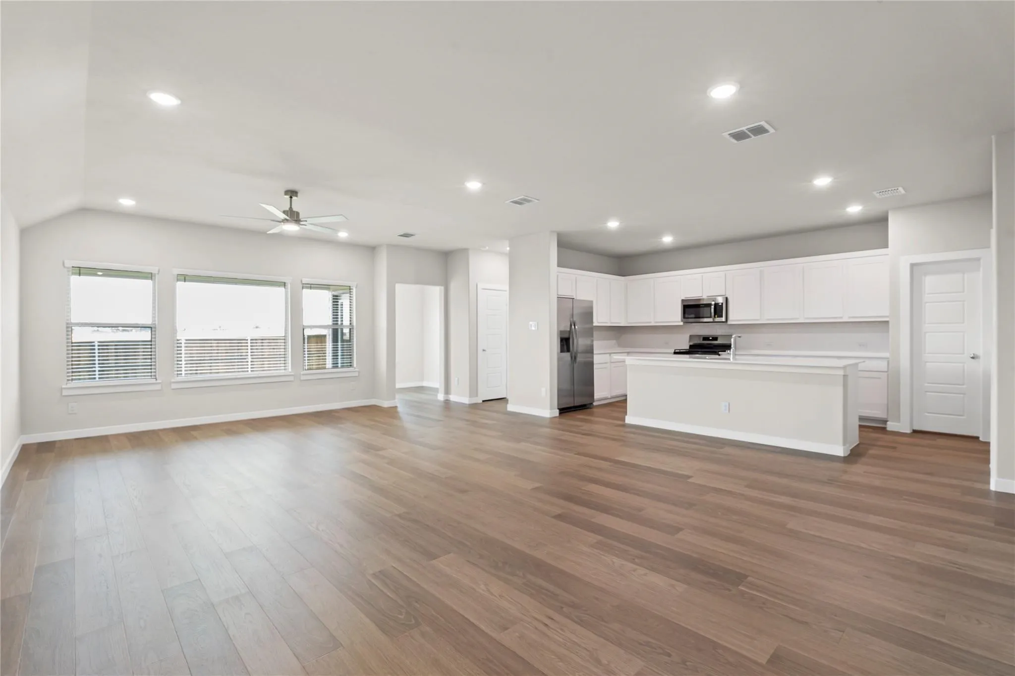 Open-concept design featuring wood-finish flooring, recessed lighting, a ceiling fan, a kitchen island, and stainless steel appliances
