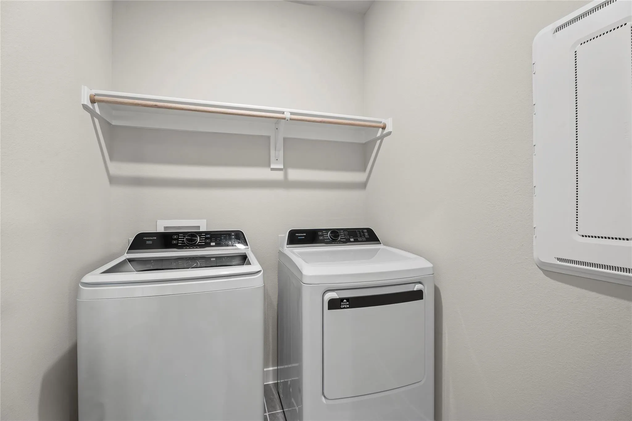 Integrated laundry area featuring shelving with a hanging rod