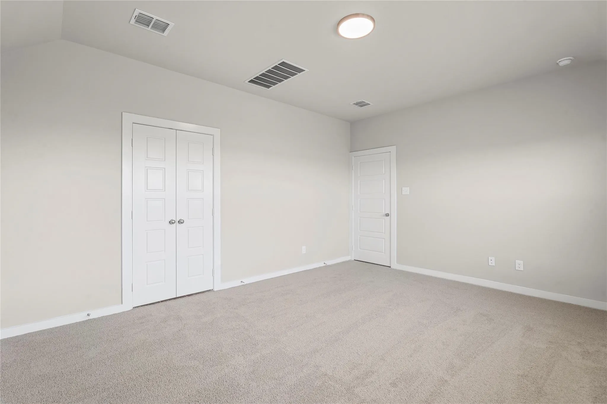 Neutral wall paint, light-toned carpeting, white interior doors, and a flush-mount ceiling light fixture