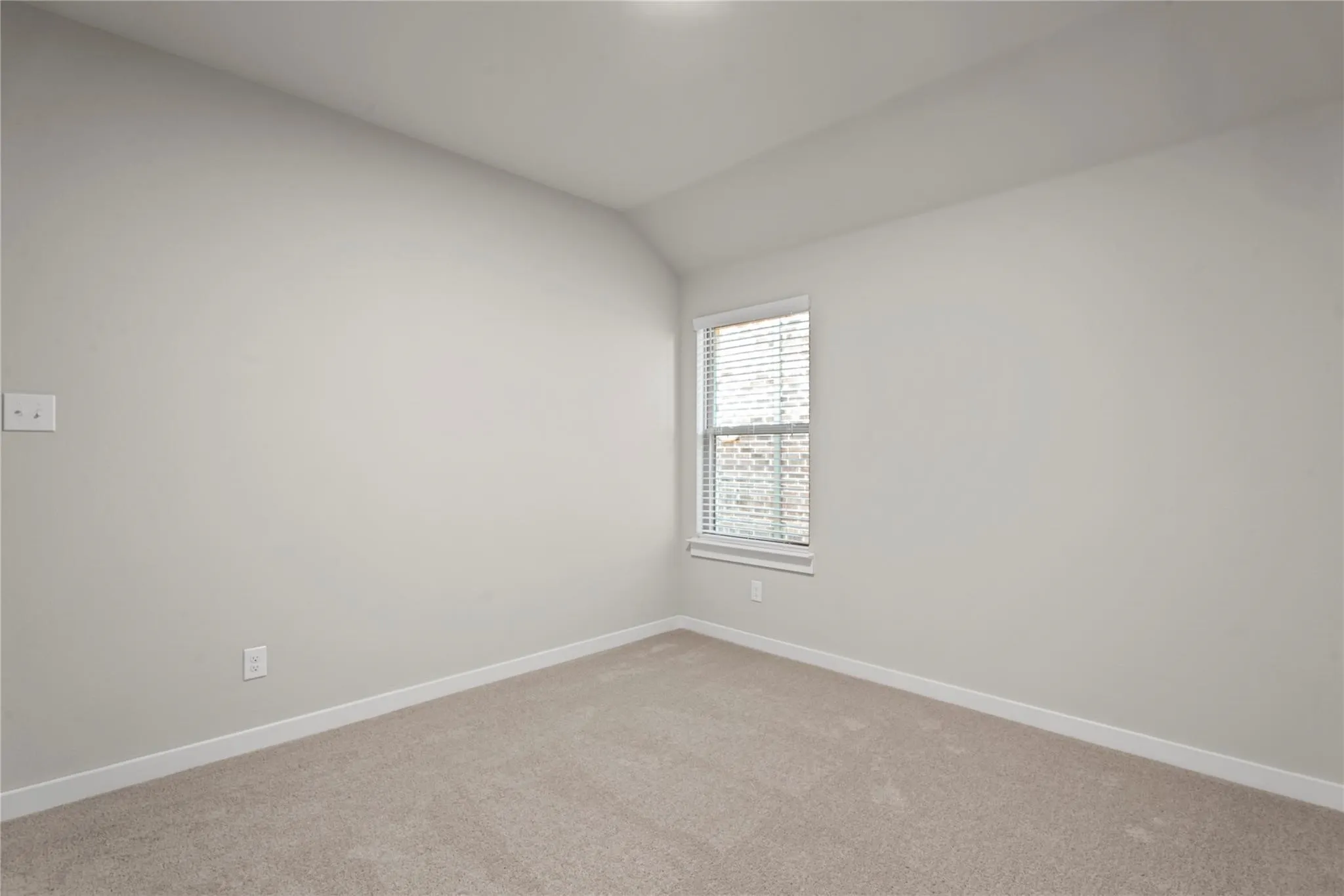 Neutral paint palette with a single window featuring blinds, textured carpeting, and white trim