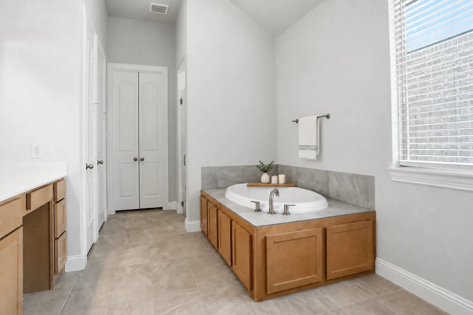 Alternate view of the spacious en suite bathroom, highlighting the soaking tub, dual vanities, separate shower, and nearby storage. Photos have been AI enhanced for presentation; no material property features were altered.
