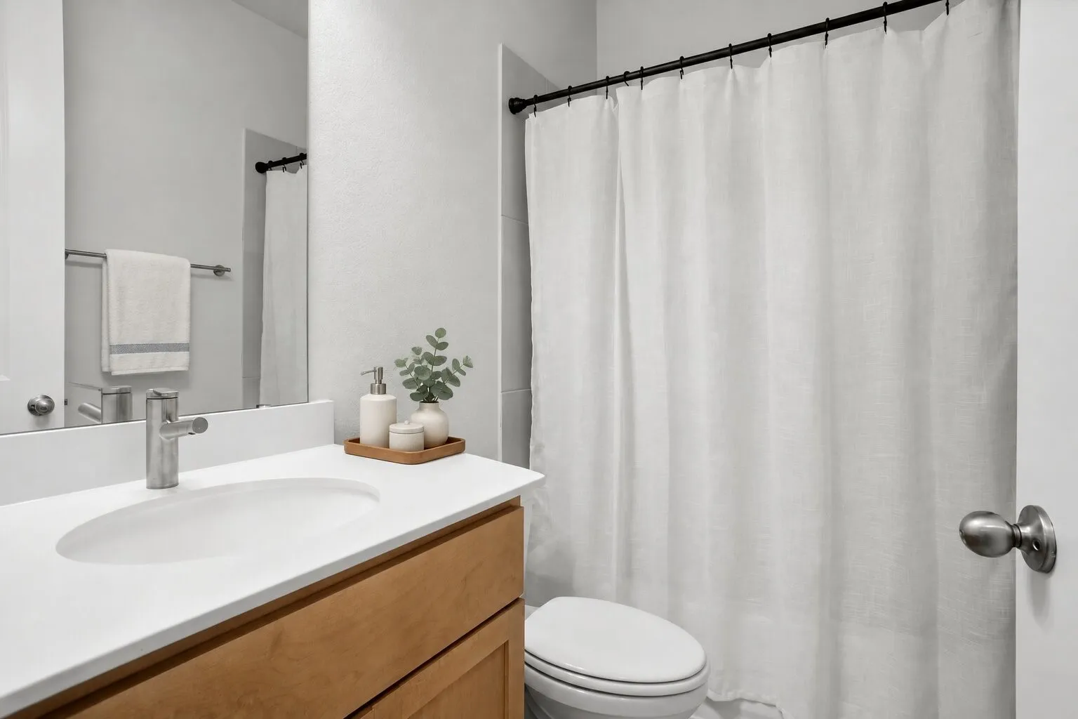 Downstairs full bathroom conveniently located near the secondary bedroom, featuring a tub-and-shower combination and generous vanity storage. Photos have been AI enhanced for presentation; no material property features were altered.