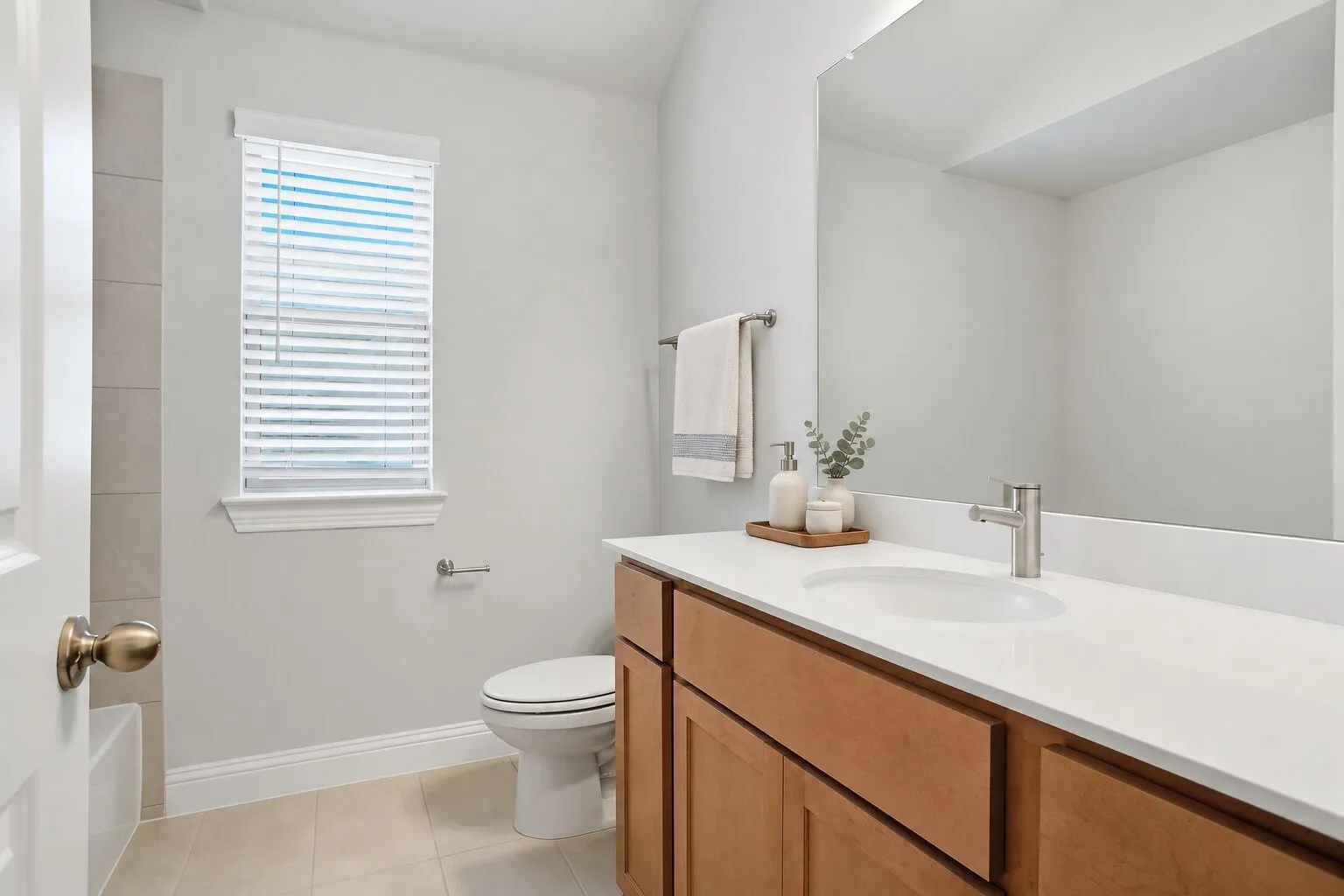 Upstairs hallway bathroom featuring a full tub-and-shower combination, generous vanity storage, and abundant natural light. Photos have been AI enhanced for presentation; no material property features were altered.