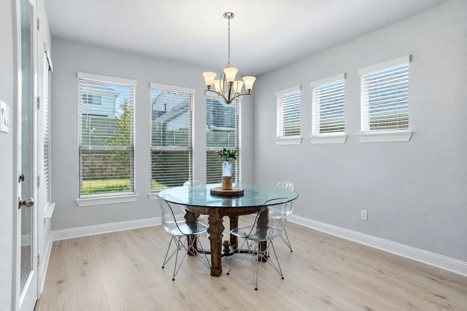 Sun-filled dining area featuring six surrounding windows, abundant natural light, and easy access to the backyard. Photos have been AI enhanced for presentation; no material property features were altered.