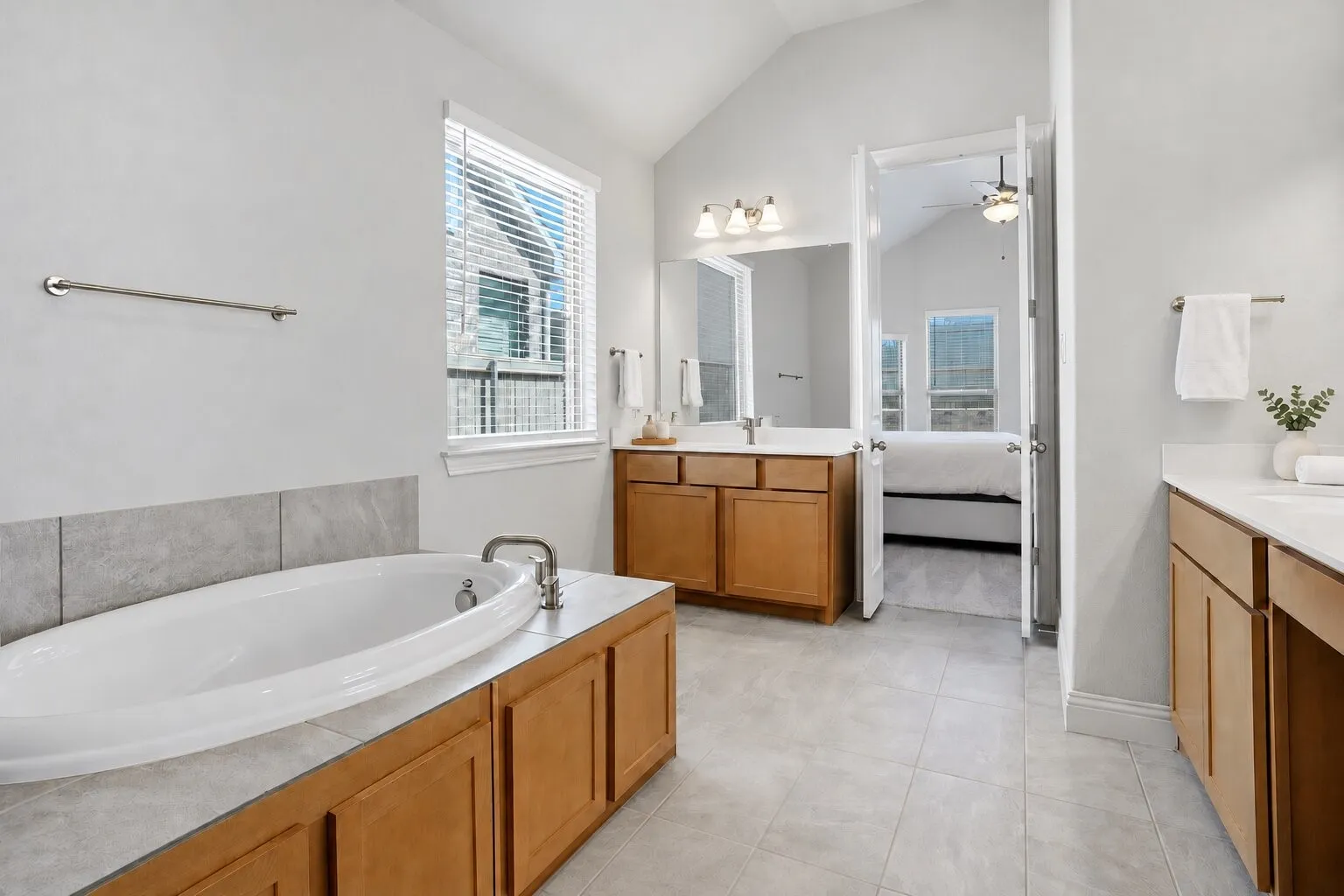 Spacious en suite bathroom featuring dual vanities, generous counter space, and a relaxing soaking tub with abundant natural light. Photos have been AI enhanced for presentation; no material property features were altered.