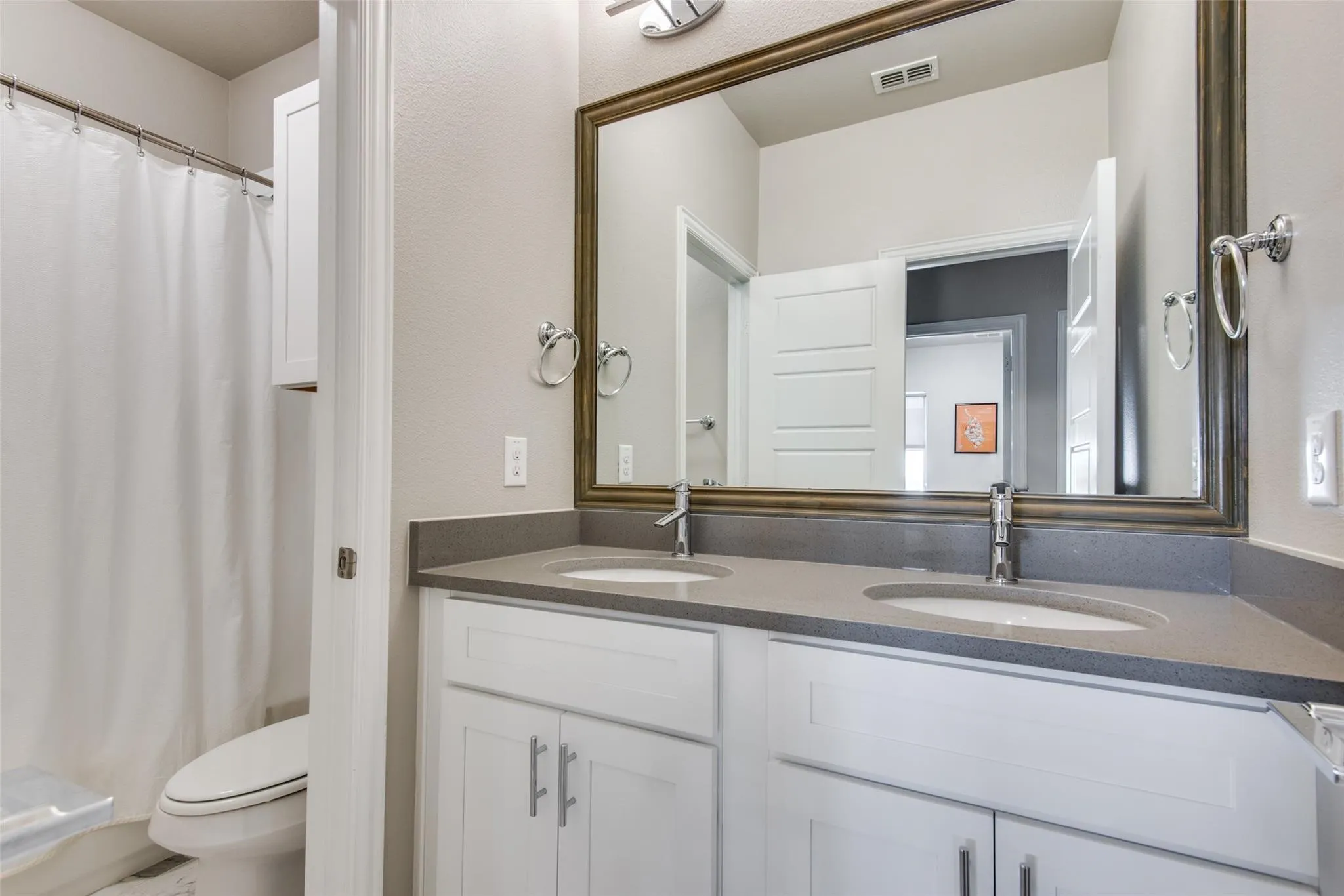 Dual vanity with undermount sinks, gray countertop, and contemporary chrome faucets