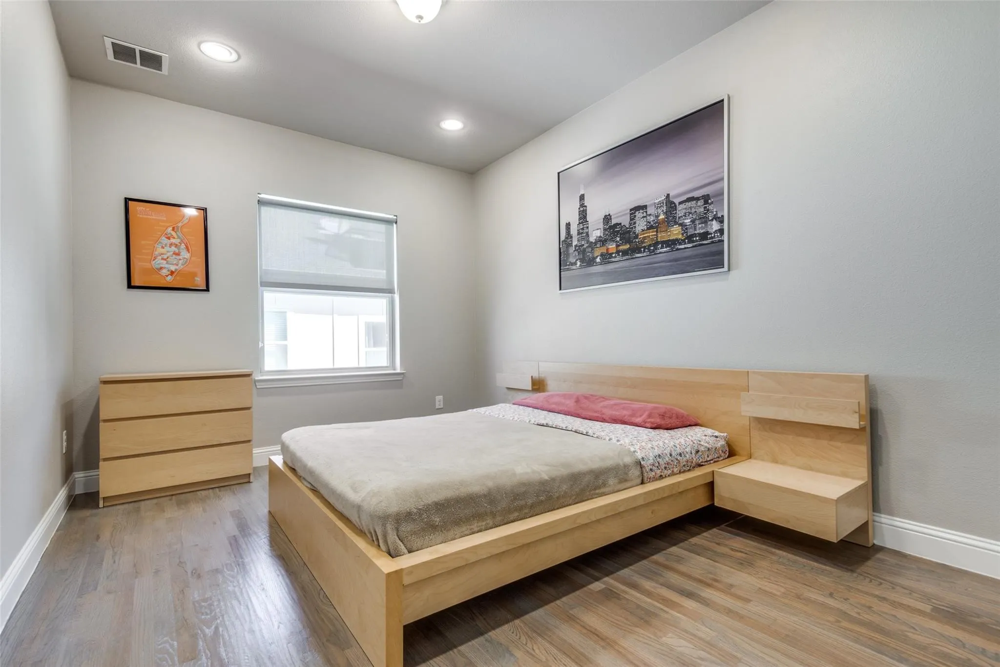 Recessed ceiling lighting, wood-finish flooring, and a window with roller shade