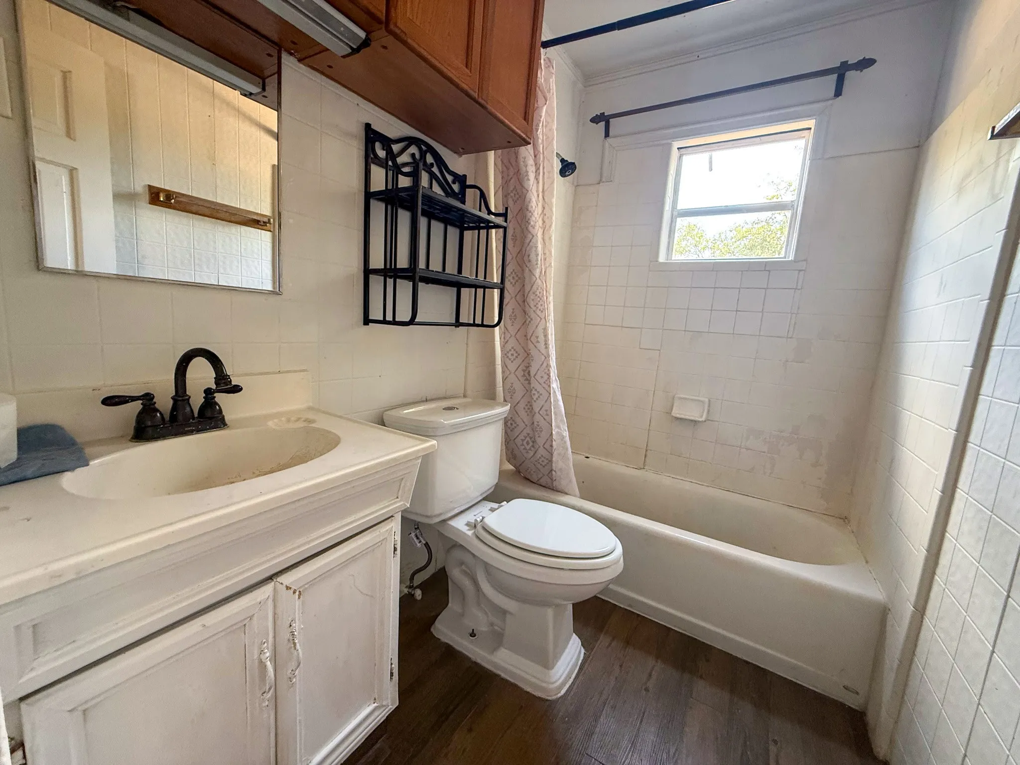 Wood-finish flooring with a white vanity featuring a single basin sink and a dark-toned faucet