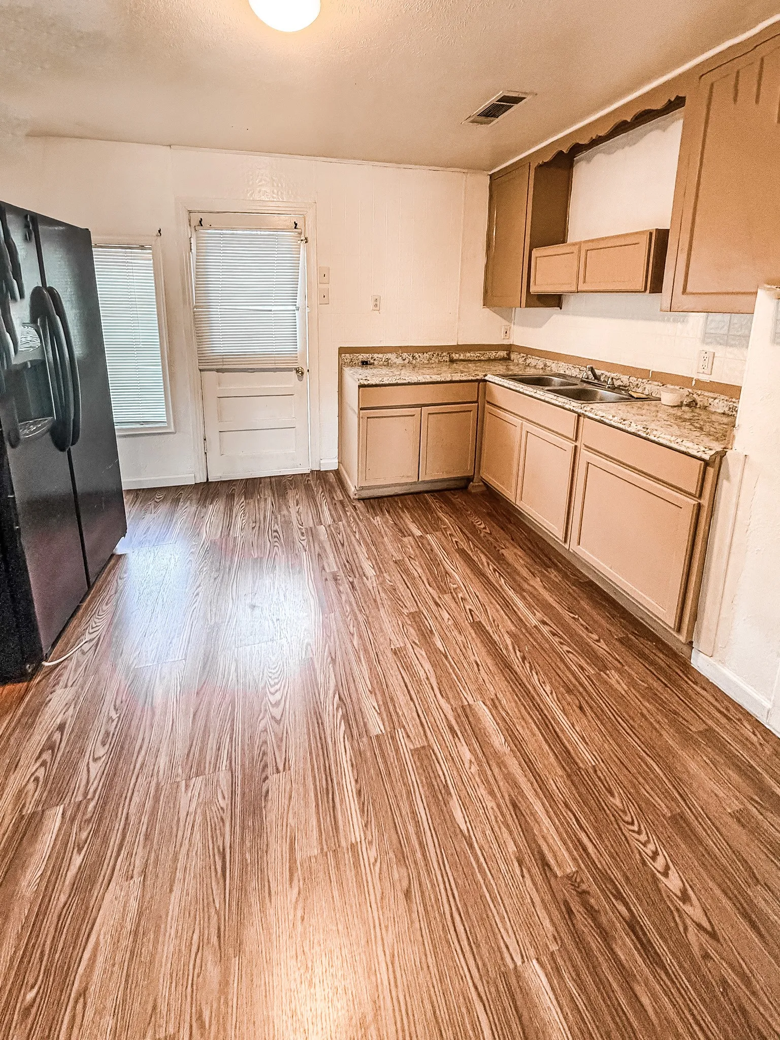 Spacious kitchen with wood-finish flooring, L-shaped countertop, and built-in cabinetry