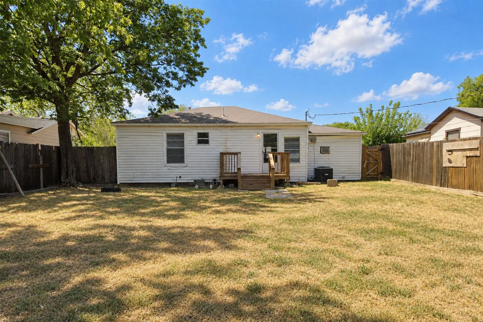Wood fencing surrounds the property with a mature tree providing shade