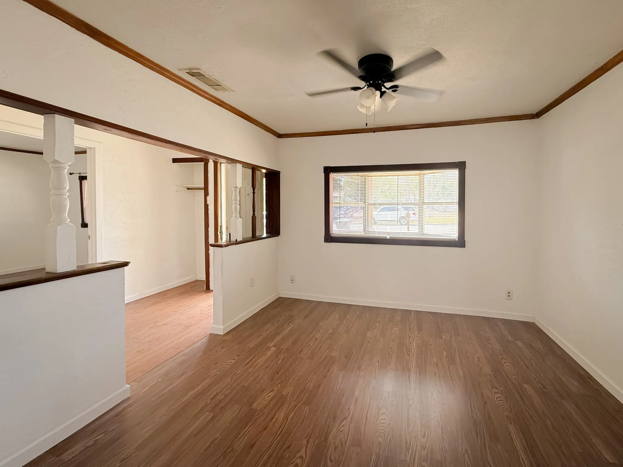 Wood-finish flooring, white walls, and a ceiling fan with integrated lighting