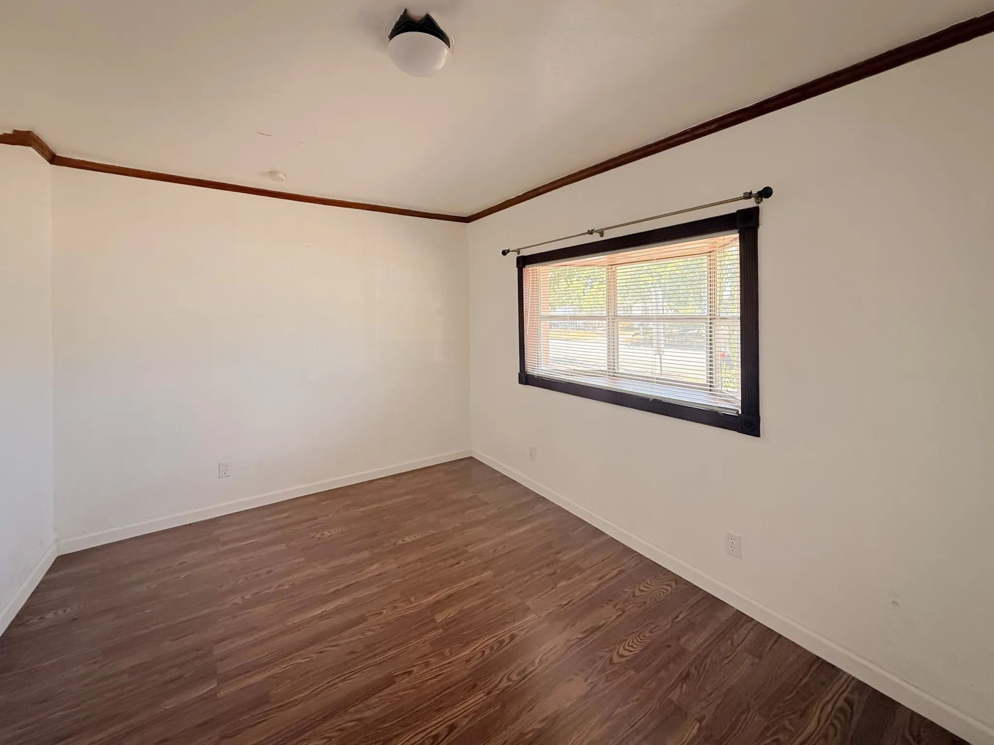 Wood-finish flooring with white walls and dark trim