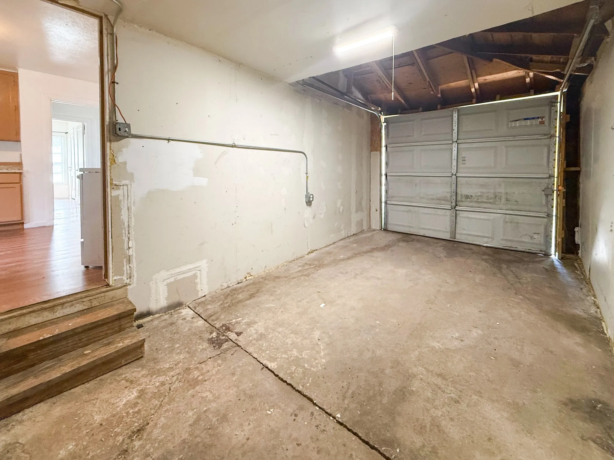 Garage space with a concrete floor, overhead lighting, and a roll-up garage door