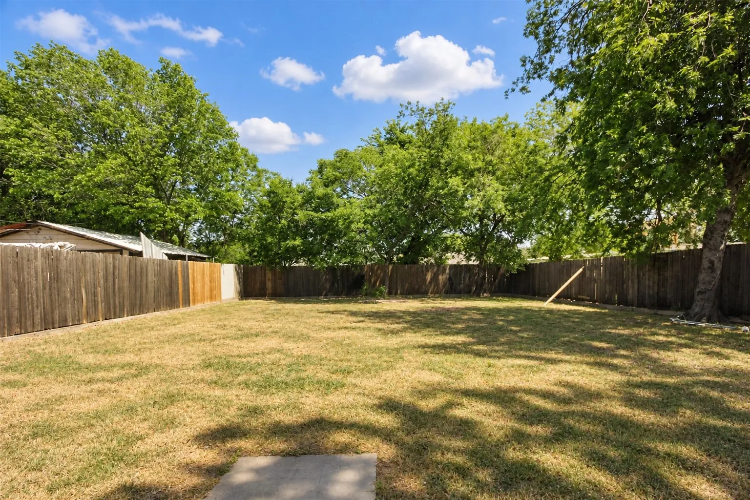 Expansive grass yard with wood fencing and mature trees