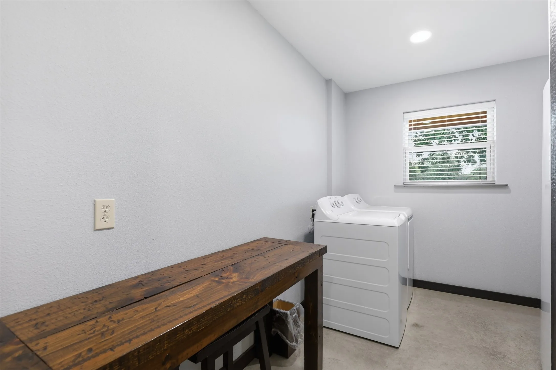 Laundry area featuring a window with blinds, recessed ceiling lighting, and concrete flooring