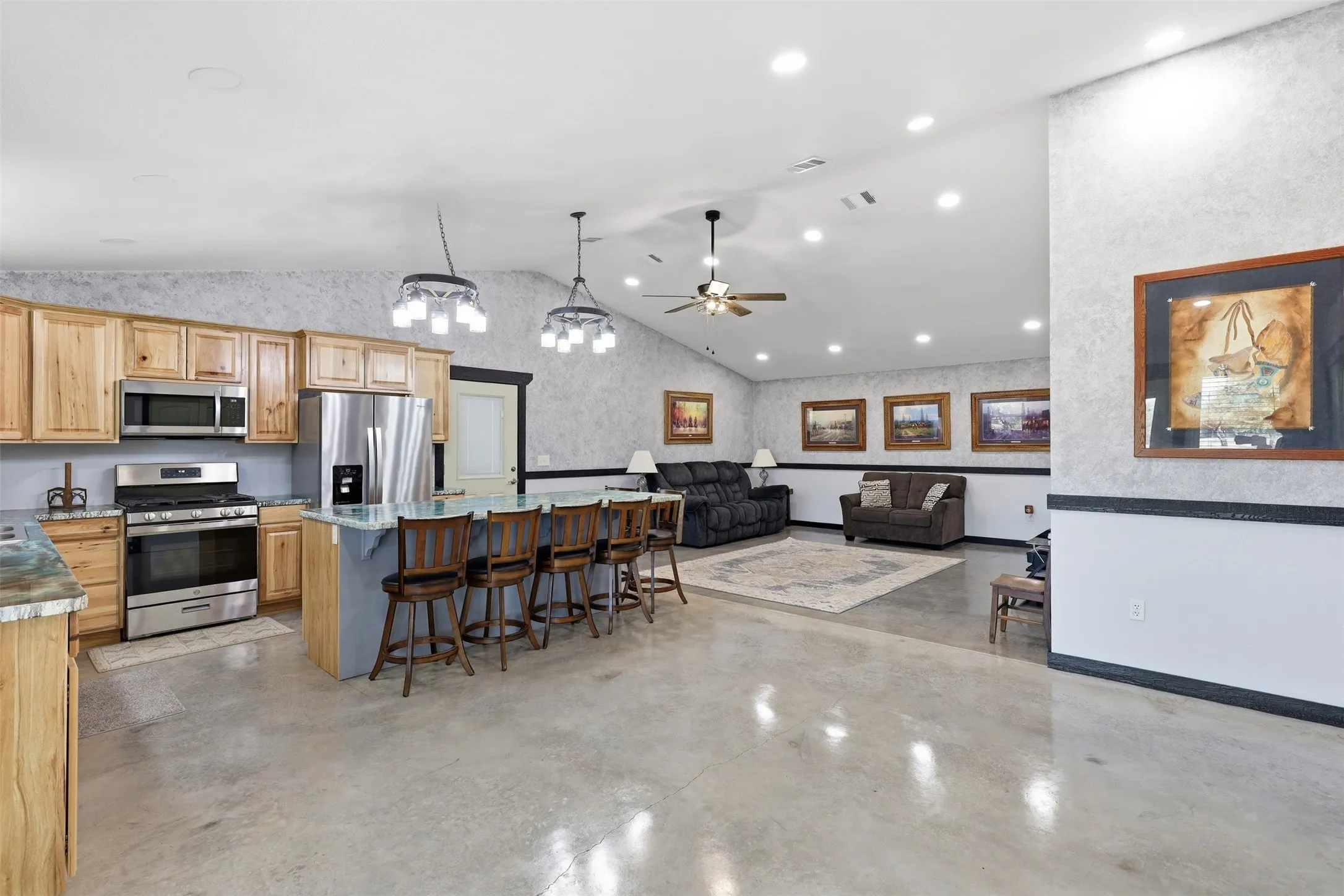 Open-concept living space featuring vaulted ceilings, recessed lighting, and polished concrete flooring
