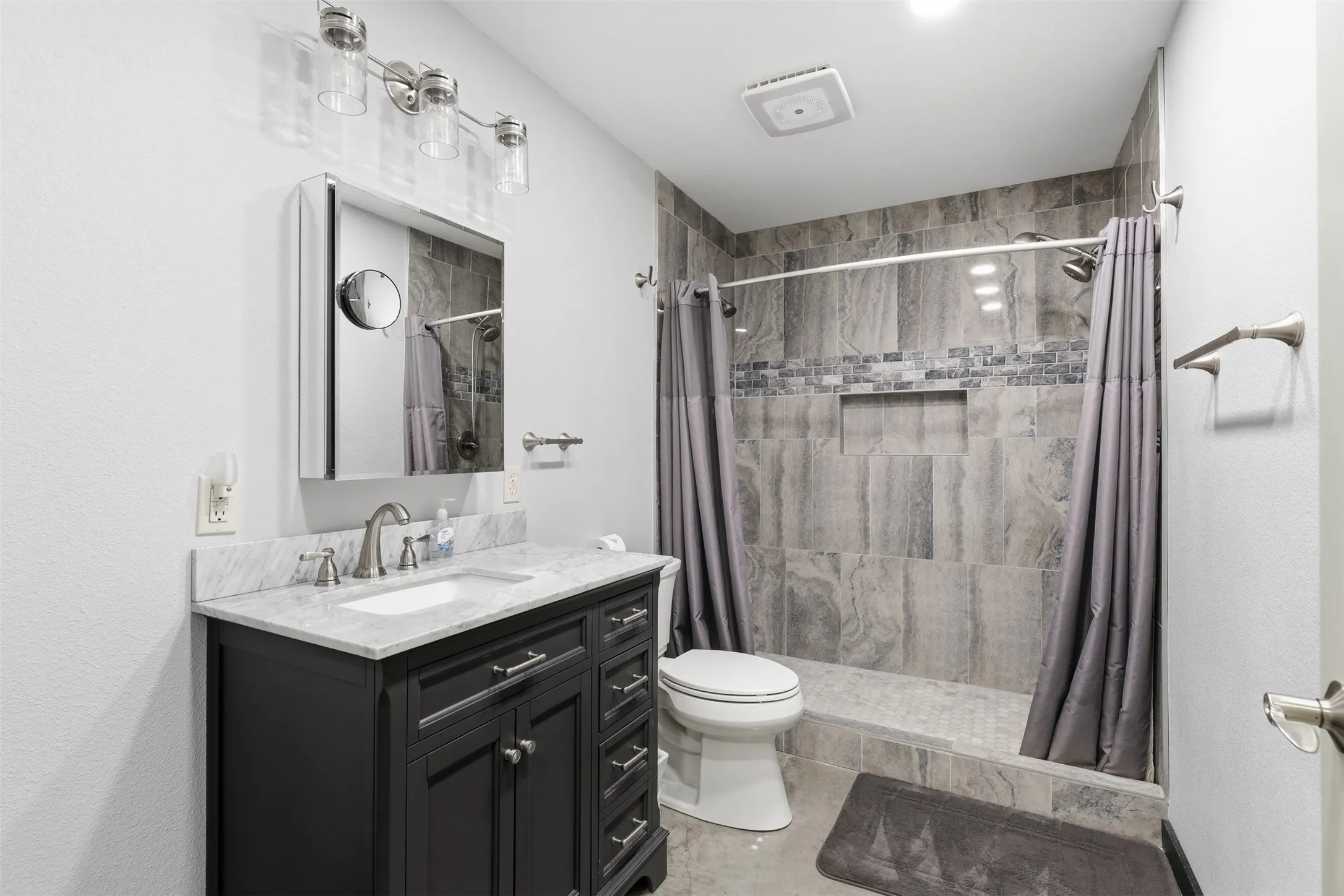 Dark wood-finish vanity with white countertop, undermount sink, and brushed nickel fixtures