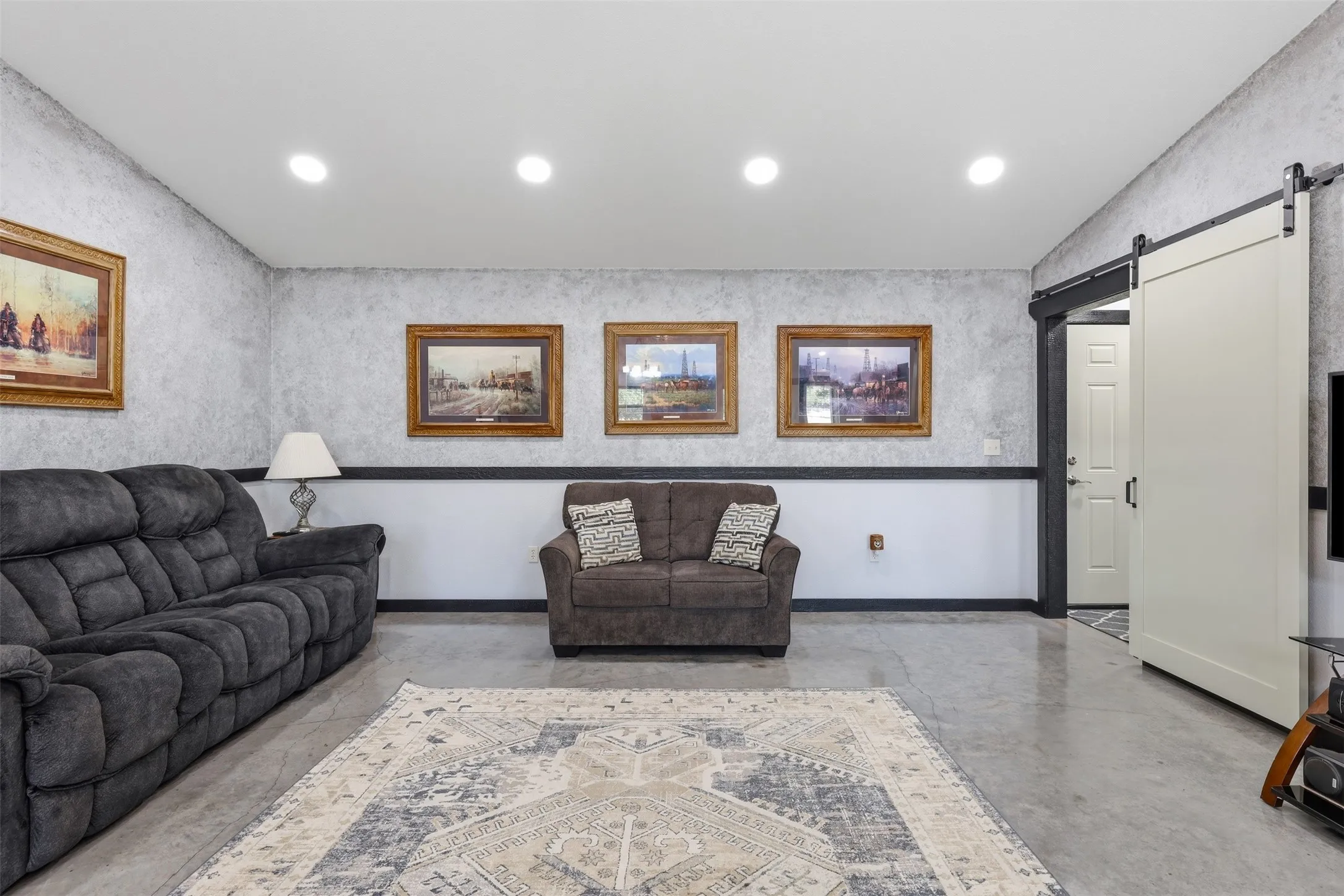 Recessed lighting, concrete flooring, two-tone wall finish, and a sliding barn door