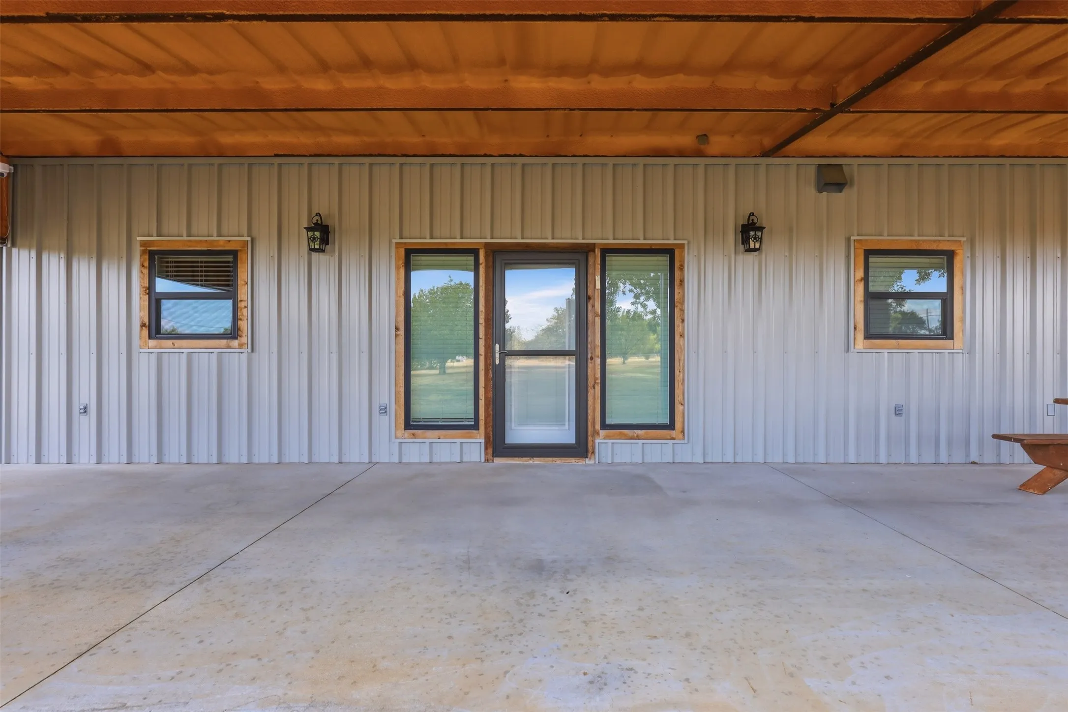 Covered patio with a concrete surface, metal siding, and a wood-paneled ceiling