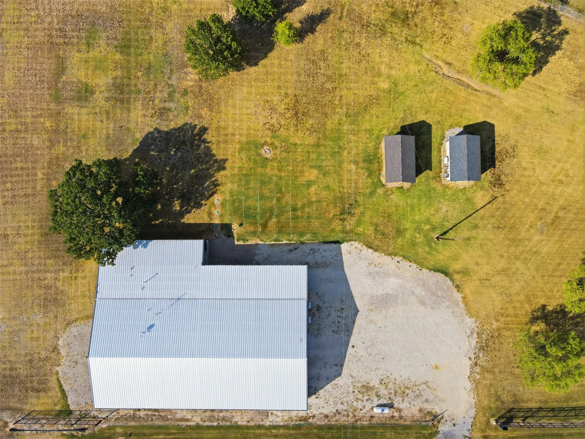 Expansive grounds featuring a substantial metal-clad outbuilding with a corrugated roof, two additional smaller structures, and a gravel drive