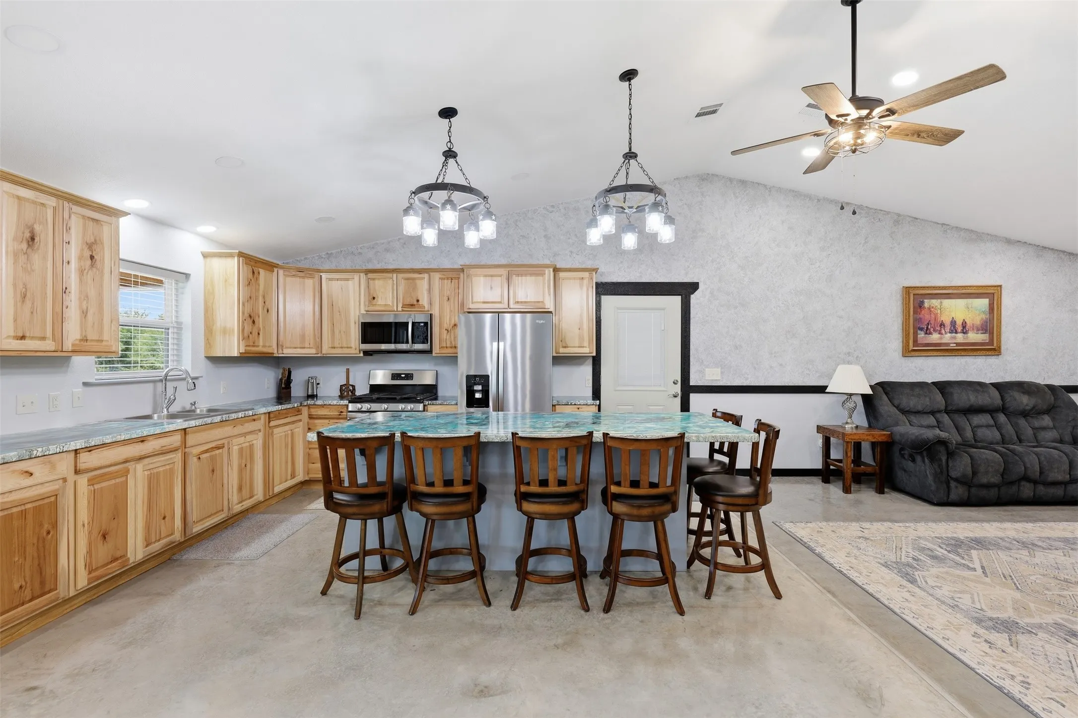 Open-concept living area featuring a vaulted ceiling and concrete flooring