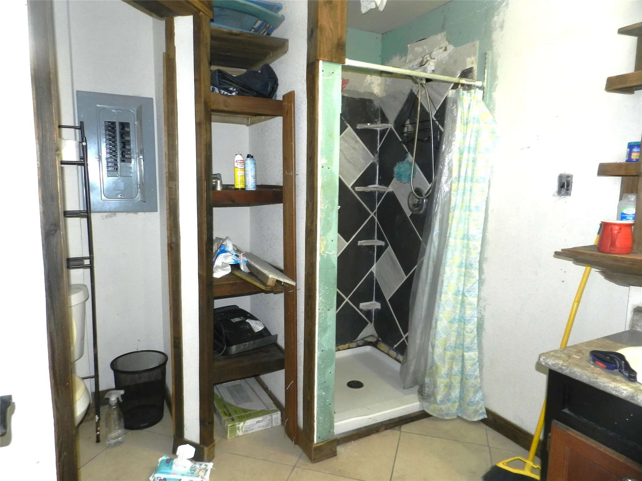 Walk-in shower with geometric tile surround, built-in shelving, and tile flooring