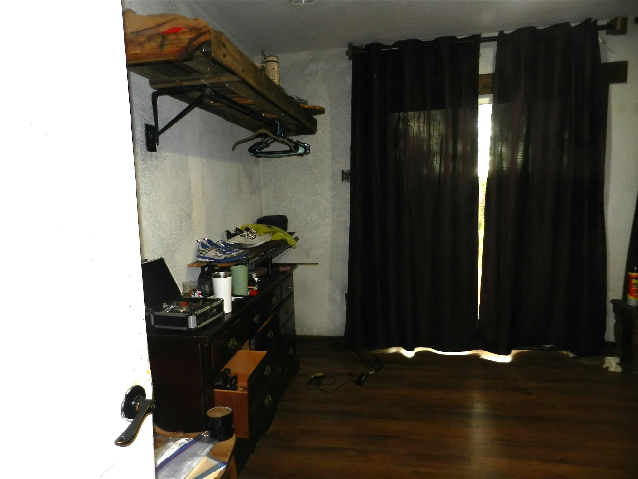 Wood-finish flooring with a window featuring dark drapery