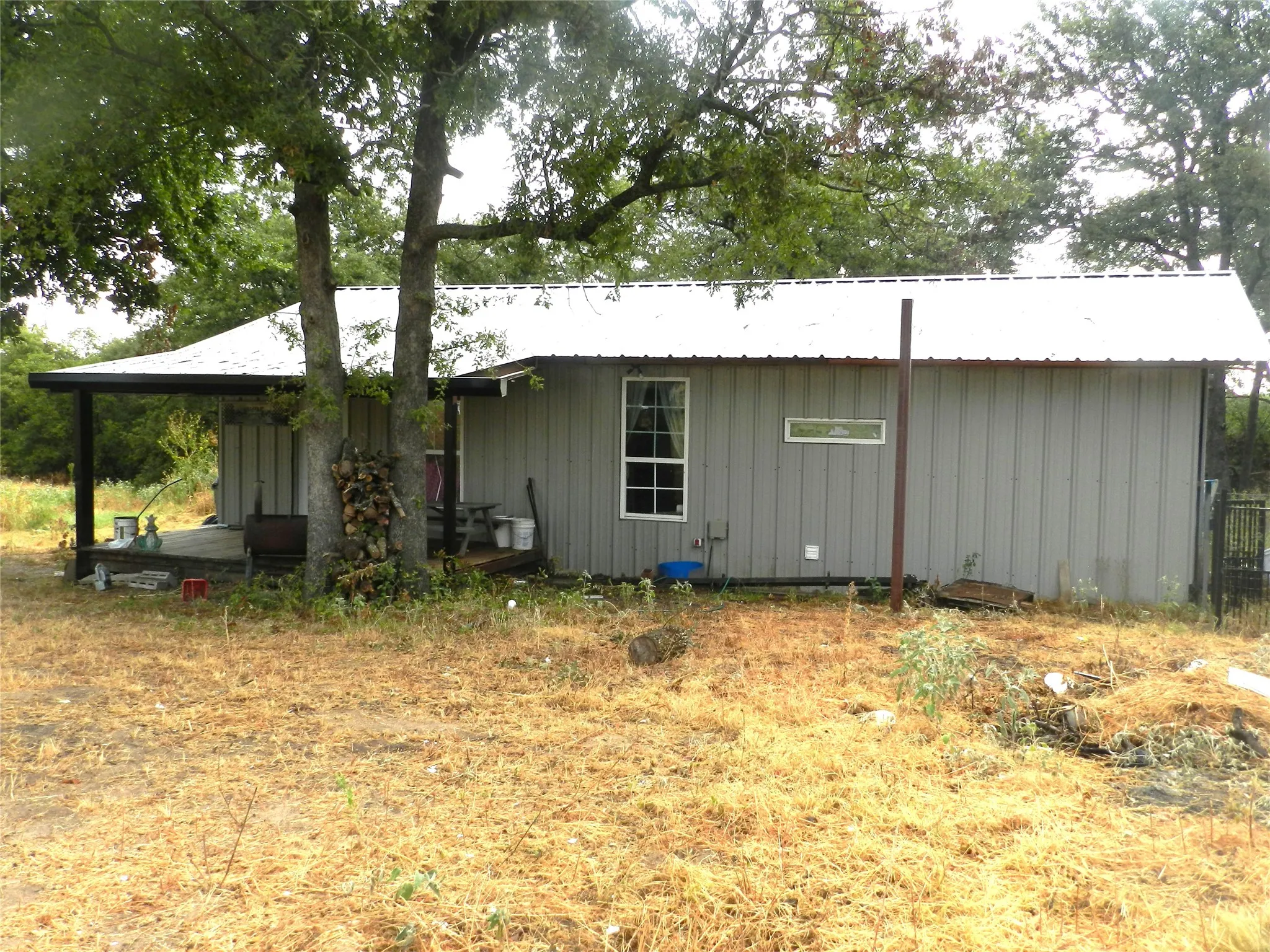 Metal siding exterior with a white metal roof, featuring a covered porch with dark support beams