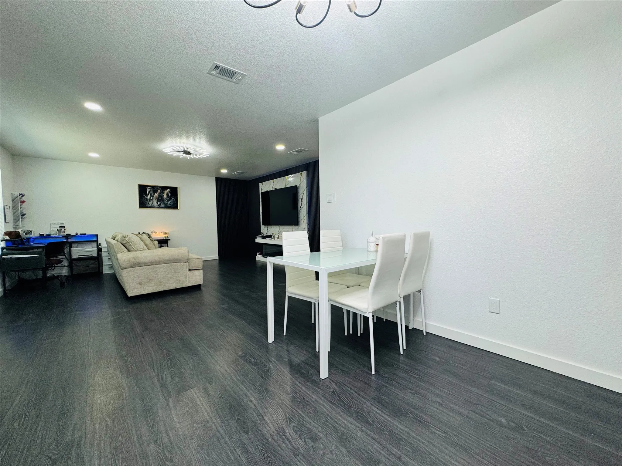 Dark wood-finish flooring throughout, recessed ceiling lighting, and a prominent chandelier fixture