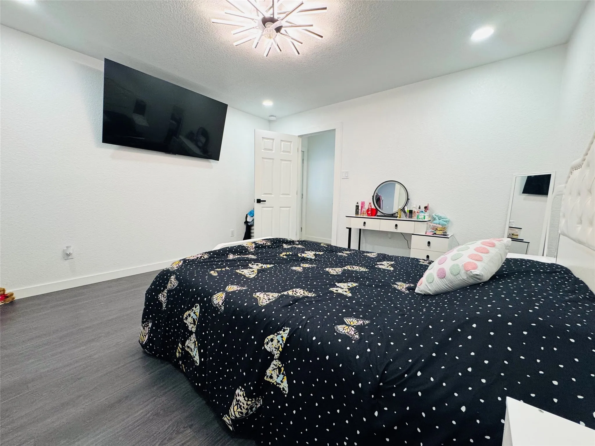 Wood-finish flooring, white paneled door, and recessed lighting