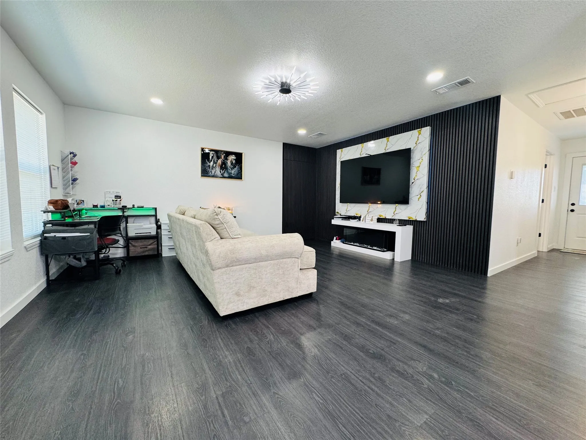 Dark wood-finish flooring with white baseboards and textured walls