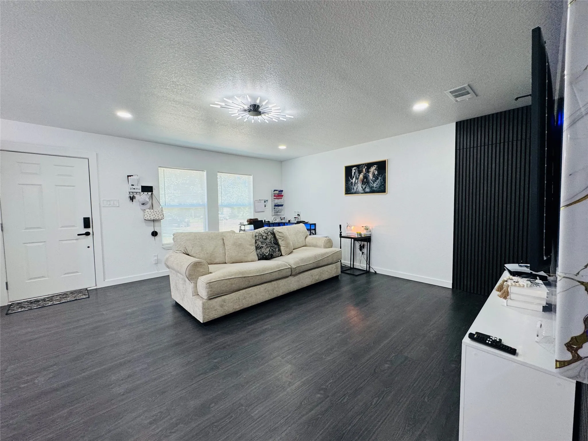 Wood-finish flooring, recessed lighting, and a decorative ceiling fixture illuminate the space