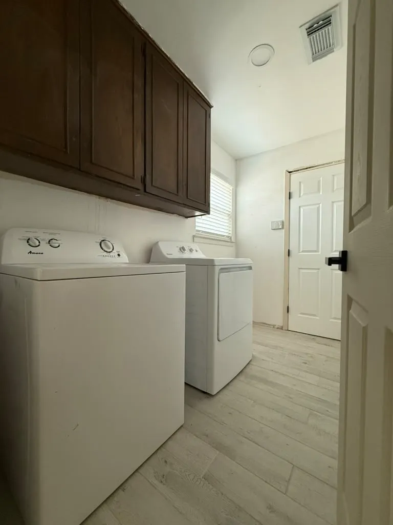 Wood-finish flooring with overhead cabinetry and a window with blinds