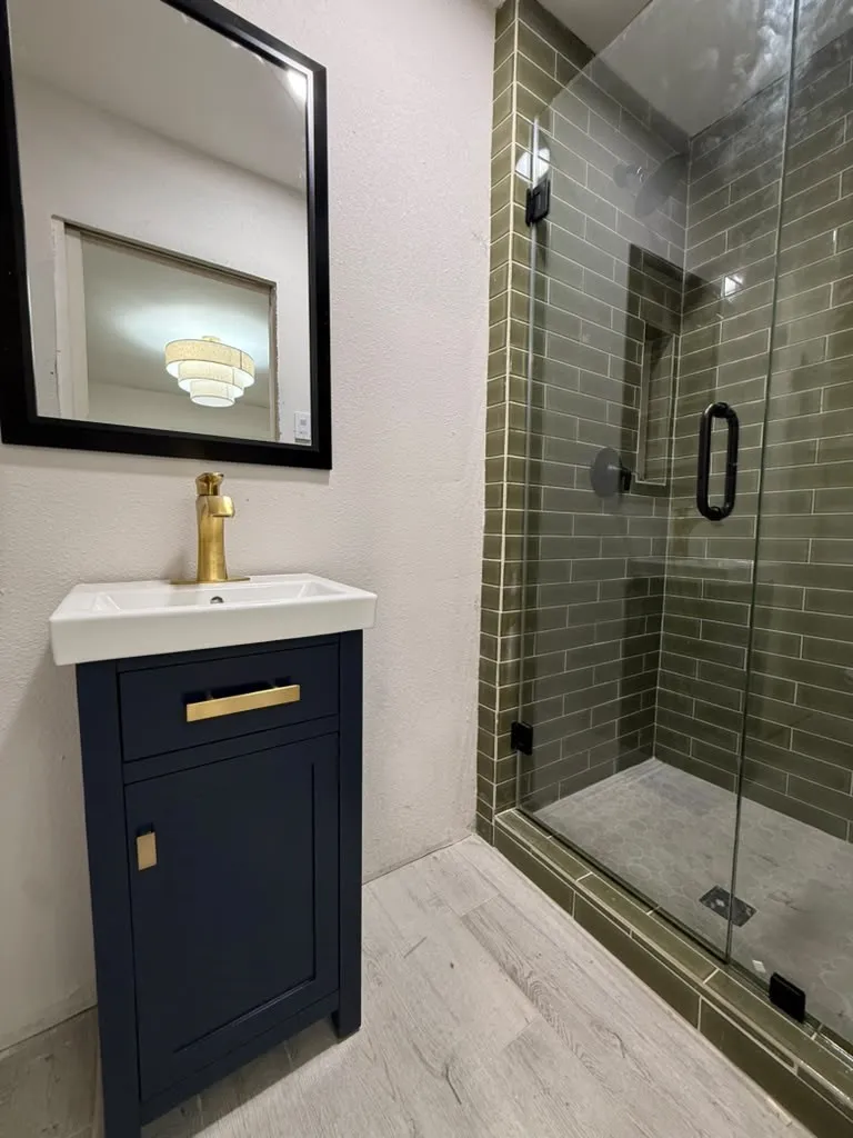 Navy blue vanity with gold-tone hardware, white rectangular basin, and a gold-tone faucet