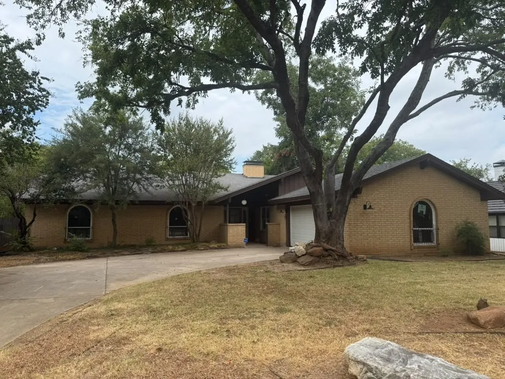 Brick exterior with an attached garage, arched windows, and a concrete driveway